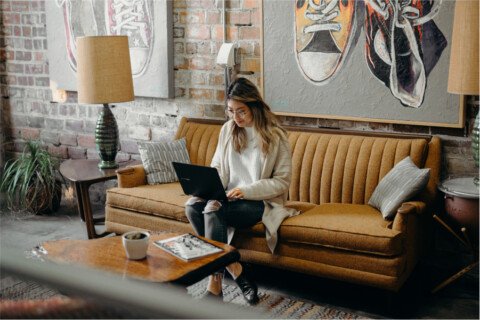 Woman working on a computer while sitting on a couch